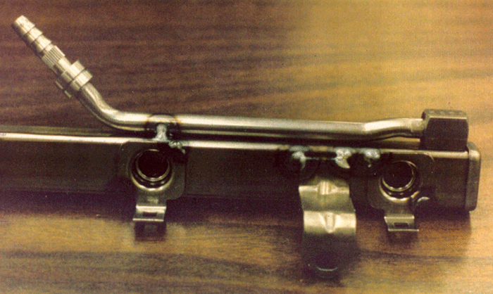 Figure 1. Fuel-rail fixtured for brazing by using large tack-welds to hold component parts in position for subsequent brazing. Note heavy oxidation around welds.