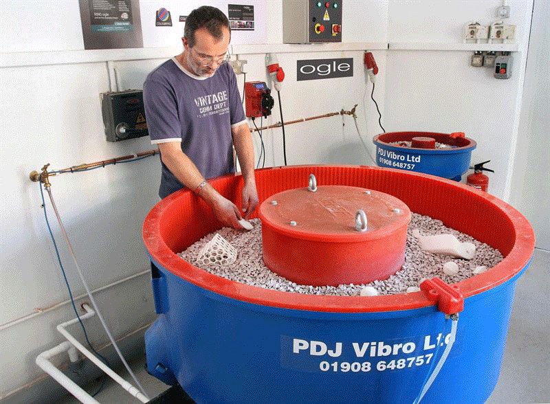 Fig. 2 A vibratory deburring machine in which the parts to be deburred are loaded into the container along with a special media which will remove burrs from the parts when those parts are tumbled within that media. (Photo courtesy of PDJ Vibro, Ltd.)