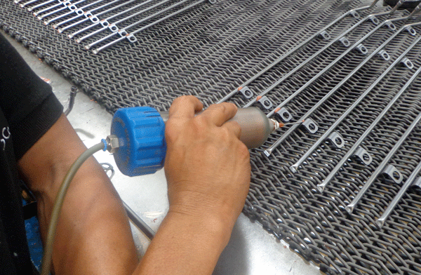 Fig. 3 Brazing paste being applied to stainless-steel parts as they steadily move past the person who is applying the paste.